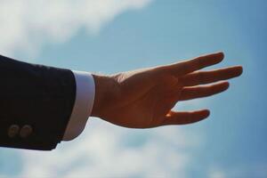 Outstretched hand against a bright blue sky, symbolizing hope and reaching for dreams photo