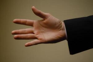 Outstretched hand in a business suit against a neutral background, symbolizing greeting photo