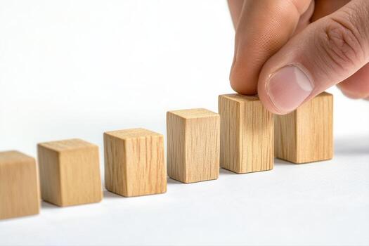 Hand arranging wooden blocks in ascending order on a white surface, symbolizing growth photo