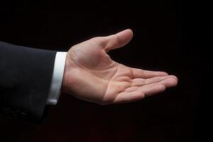 Open hand gesture in formal attire against a dark background, symbolizing invitation photo