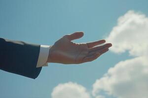 Outstretched hand in a suit against a bright blue sky with fluffy clouds, symbolizing hope photo