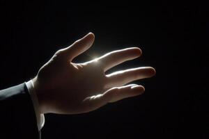 Illuminated hand reaching out against a dark background, symbolizing connection and hope photo
