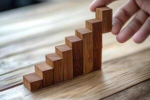 Wooden blocks arranged in a staircase formation, hand adjusting the top piece, warm tones photo