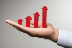 Hand holding red upward arrows representing growth and success in a minimalist setting photo