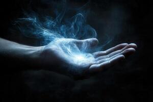 Mysterious hand conjuring ethereal blue energy in a dark, atmospheric setting photo