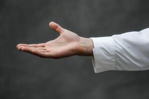 Outstretched hand in a white shirt against a blurred gray background, inviting gesture photo