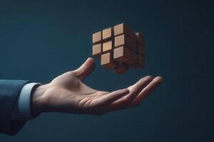 Hand holding a levitating wooden puzzle cube against a dark background, symbolizing creativity photo