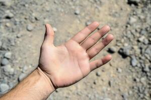 Open hand reaching out over a rocky ground, showcasing texture and natural elements photo