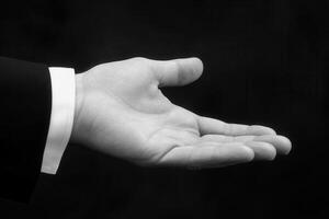 Open hand gesture in a formal setting, symbolizing invitation or request, with a dark background photo