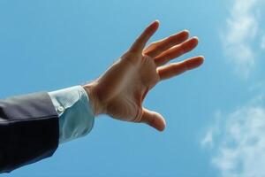 Outstretched hand reaching towards a clear blue sky, symbolizing aspiration and hope photo