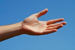 Outstretched hand reaching towards a clear blue sky, symbolizing hope and connection photo