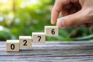 Hand placing wooden blocks with numbers in ascending order on a rustic table amidst greenery photo
