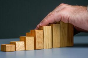 Hand arranging wooden blocks in ascending order on a table, symbolizing growth and progress photo