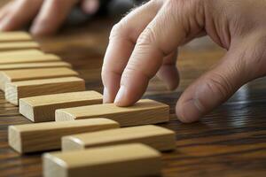 Hand arranging wooden blocks in a strategic manner on a wooden table, showcasing focus photo
