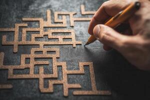 Hand with pen tracing intricate maze pattern on textured surface, showcasing creativity photo