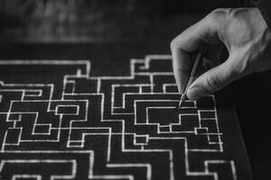 Hand drawing intricate maze patterns on black paper with pencil in artistic workspace photo