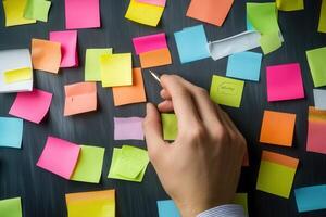 Hand writing on colorful sticky notes scattered on a desk, showcasing brainstorming ideas photo