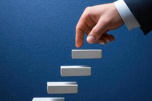 Hand reaching for ascending blocks against a blue background, symbolizing progress and achievement photo
