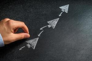 Hand drawing arrows on a chalkboard to symbolize growth and progress in business strategy photo
