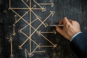 Hand drawing complex directional arrows on a chalkboard, illustrating strategic planning photo