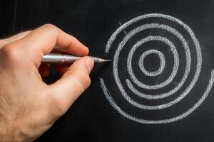 Hand drawing concentric circles on a blackboard with a pencil, showcasing creativity and focus photo