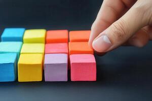 Hand arranging colorful wooden blocks in a creative pattern on a dark surface photo
