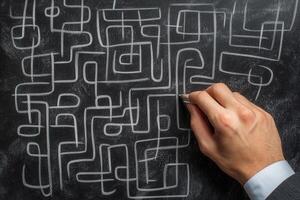 Hand drawing intricate maze patterns on a blackboard with chalk in a creative workspace photo