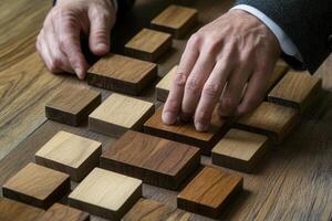 Hands arranging various wooden blocks on a table, showcasing craftsmanship and design photo