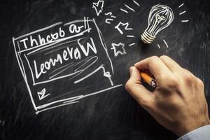 Hand drawing creative ideas on a chalkboard with a light bulb and stars in the background photo