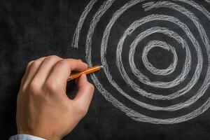 Hand drawing concentric circles on a blackboard with an orange pen, creative brainstorming session photo