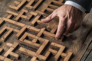 Hand manipulating intricate wooden puzzle pieces on a rustic surface, showcasing craftsmanship photo