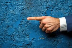 Hand pointing against a textured blue wall, emphasizing direction and focus photo