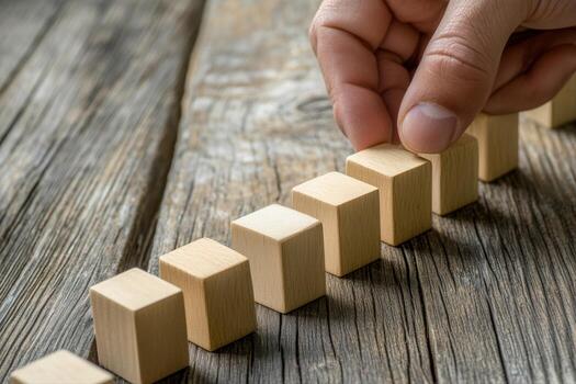 Hand arranging wooden blocks in a line on a rustic wooden table, showcasing creativity photo