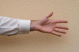 Outstretched hand against a textured wall, symbolizing invitation or greeting gesture photo