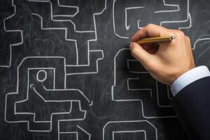 Hand drawing a complex maze on a chalkboard, symbolizing problem-solving and strategy photo