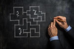 Hands of a business professional sketching a complex maze on a chalkboard background photo