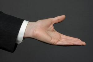 Outstretched hand in formal attire against a dark background, symbolizing invitation or agreement photo