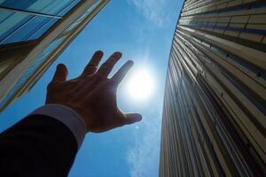 Reaching for the Sun A Hand Extends Towards the Bright Sky Between Tall Buildings photo