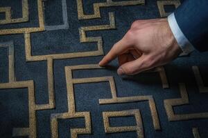 Hand pointing at a maze pattern on a textured surface, symbolizing problem-solving photo