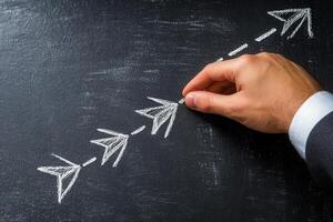 Hand drawing arrows on a chalkboard, illustrating progress and direction in business strategy photo