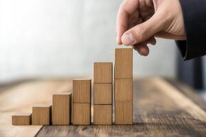 Hand placing wooden block on growth chart, symbolizing progress and success in business photo
