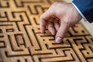 Hand navigating a wooden maze puzzle, showcasing focus and problem-solving skills photo