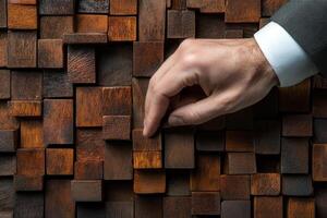 Hand adjusting wooden blocks in a textured wall, showcasing craftsmanship and design photo
