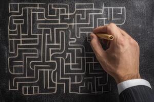 Hand drawing a complex maze on a chalkboard, illustrating problem-solving and creativity photo