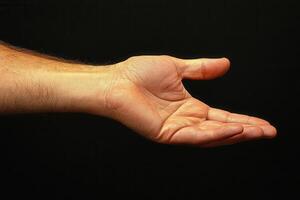Open hand gesture against a dark background, symbolizing invitation or support photo