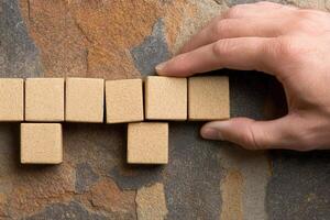 Hand arranging wooden blocks on a textured stone surface, showcasing creativity and focus photo