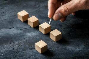 Hand arranging wooden blocks on a dark surface, symbolizing creativity and strategy photo