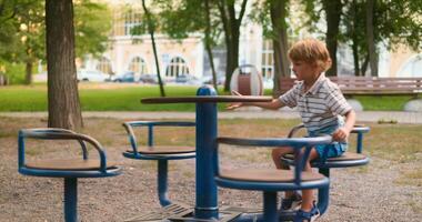 Boy playing on playground carousel in park video