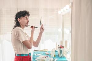Young non-binary person applying makeup in front of mirror photo