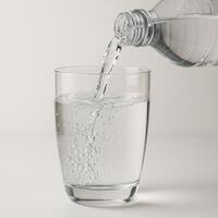 Crystal Clear Mineral Water Pouring from Bottle into Glass with Bubbles photo